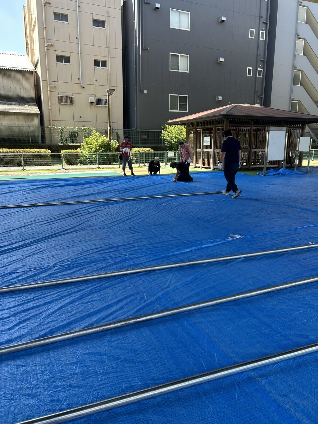 駐輪場にブルーシートを敷く準備作業